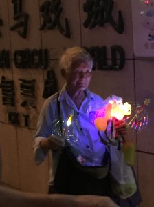 Old lady selling things that glow in the night